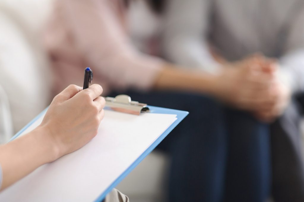 Psychologist writing in blank notepad at family counseling session